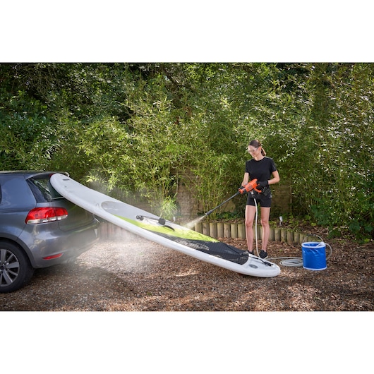 BLACK+DECKER BCPC20D1 portable pressure washer cleaning paddleboard outdoors, product in use.