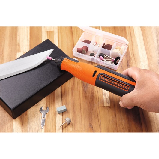 BLACKDECKER BCRT8K35 rotary tool used for sharpening a knife, accessories set visible on wooden surface.