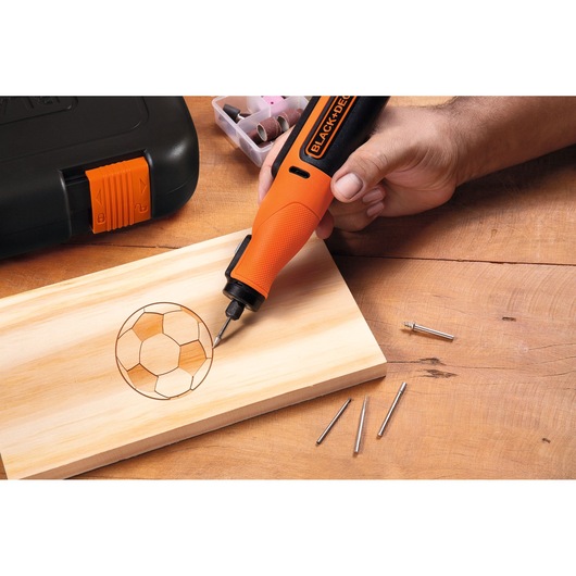 BLACKDECKER BCRT8K35 rotary tool engraving a soccer ball design on wood, accessories and case visible.
