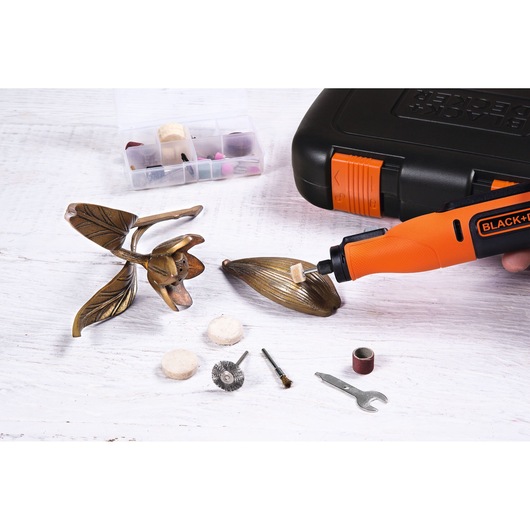 BLACKDECKER BCRT8K35 rotary tool kit with accessories, polishing a metal decoration, flat lay angle.
