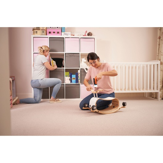 BLACKDECKER BCRTA601I cordless screwdriver in use assembling a child's wooden rocker toy in a nursery room, side angle.