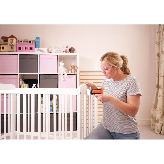 Photo of a woman using a BLACKDECKER BCRTA601I cordless screwdriver to assemble a white baby crib in a nursery.