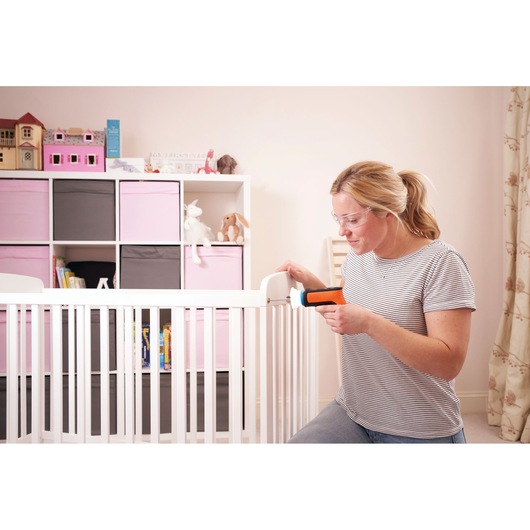 BLACKDECKER BCRTA601I cordless screwdriver used by a woman assembling a white crib in a nursery.