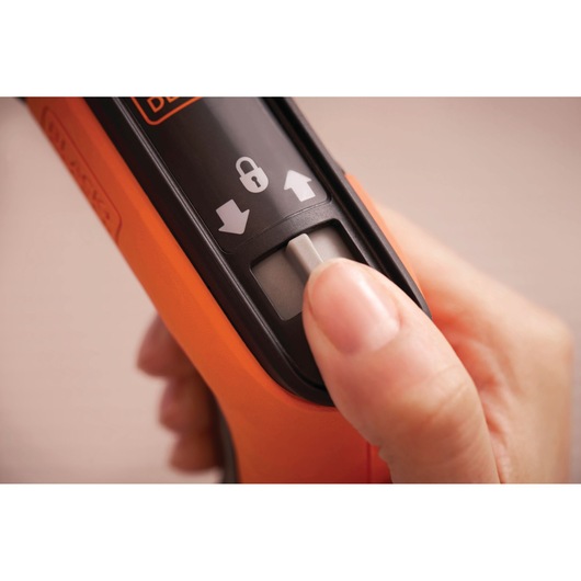 Close-up photo of a hand using the BLACKDECKER BCRTA601I tool slider switch with lock and directional arrows.