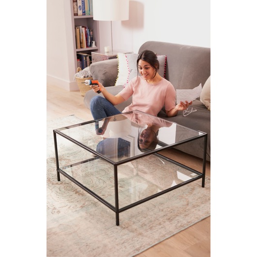 BLACKDECKER BCRTA601I electric screwdriver held by person assembling glass coffee table in living room