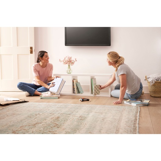 BLACKDECKER BCRTA601I cordless screwdriver on floor with two people organizing books in living room.