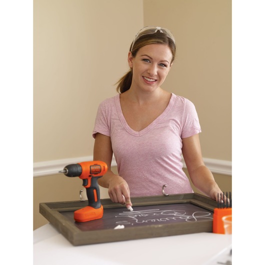 Photo of BLACKDECKER BDCD8C cordless drill in orange and black on a chalkboard frame with accessories.