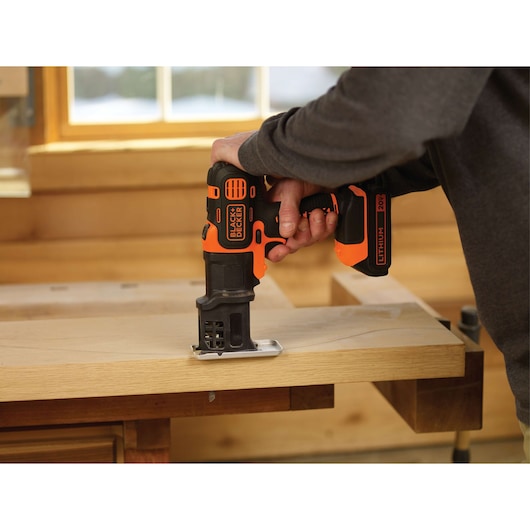 Photo of BLACK+DECKER BDCMTJS cordless jigsaw cutting wood, shown in use in a workshop setting.