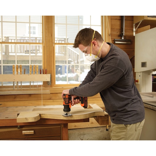 BLACKDECKER BDCMTR woodworking tool in use, person drilling wood board in workshop setting.
