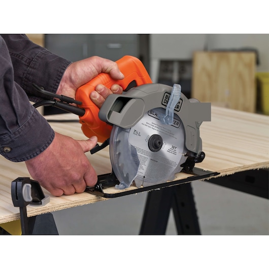 Photo of BLACK+DECKER BDECS300C circular saw cutting wood, close-up of hands operating the tool indoors.