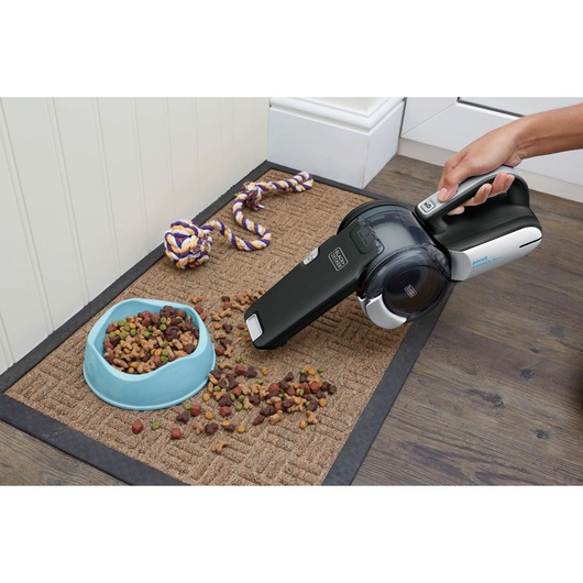 BLACKDECKER BDH2000PL handheld vacuum cleaning spilled pet food from mat, close-up photography.