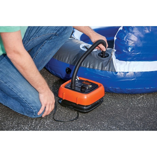 BLACKDECKER BDINF12C portable inflator in use inflating a blue and gray pool float outdoors.