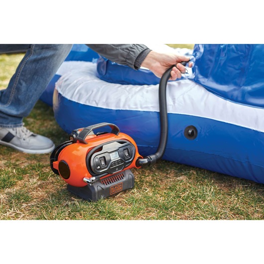 BLACKDECKER BDINF20 orange inflator in use inflating a blue inflatable outdoor item on grass.