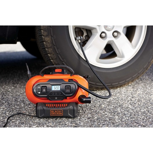 BLACKDECKER BDINF20 orange digital tire inflator in use with a car tire, photography outdoors.