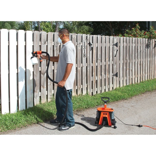 Photo of BLACKDECKER BDPH1200 paint sprayer used outdoors to paint a wooden fence.