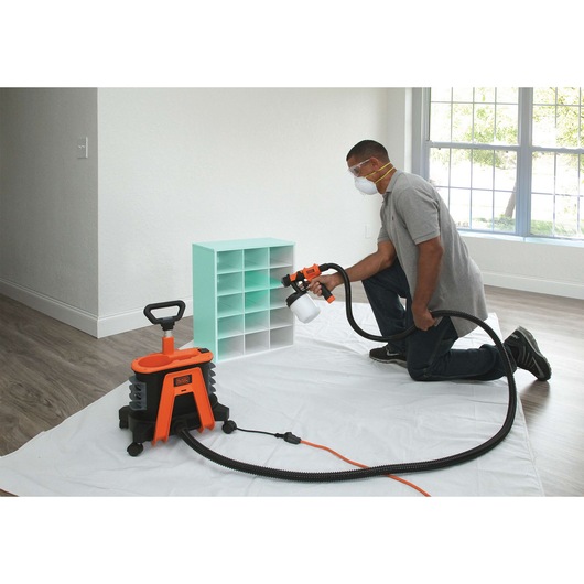 BLACKDECKER BDPH1200 paint sprayer in use painting a small shelving unit indoors.