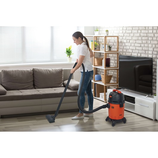 Photo of BLACKDECKER BDWD10 wet and dry vacuum in use cleaning a living room floor near a sofa.