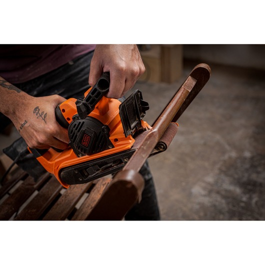BLACKDECKER BEBS0900 belt sander used on wooden furniture, close-up photography.