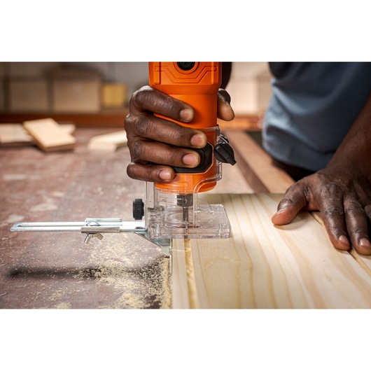 BLACKDECKER BETR0500 compact router in use on light wood plank, close-up of hands guiding tool.