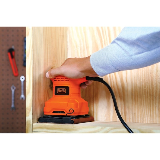 Photo of BLACKDECKER BS200 orange sheet sander being used on light wood surface.
