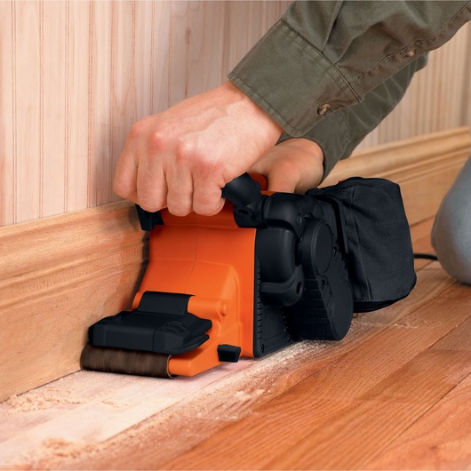 BLACKDECKER DS321 belt sander sanding wooden floor edge, close-up view in use.