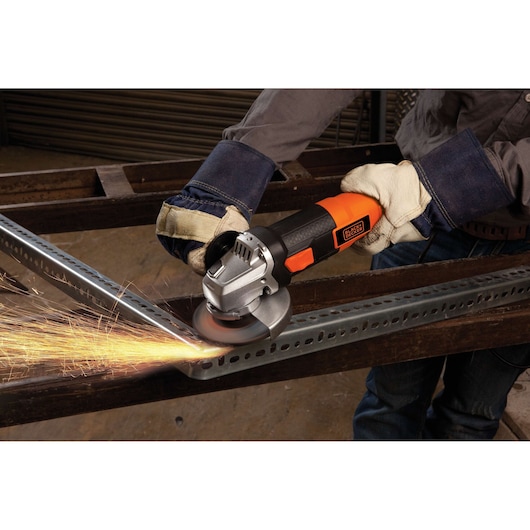 BLACKDECKER G720 angle grinder in use, grinding metal with sparks flying, worker wearing gloves.
