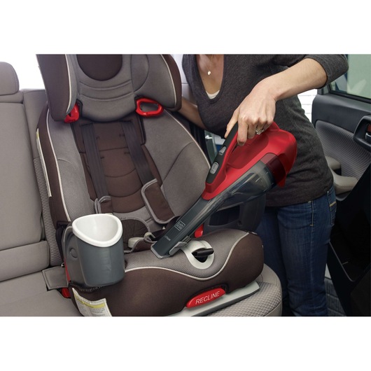 BLACKDECKER HLVA320J26 handheld vacuum cleaning a child car seat in rear vehicle interior.