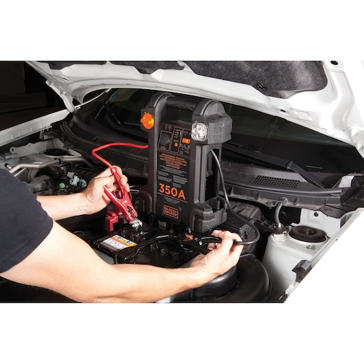 Photo of BLACK+DECKER JS350CC jump starter in use, connected to a car battery under the hood.