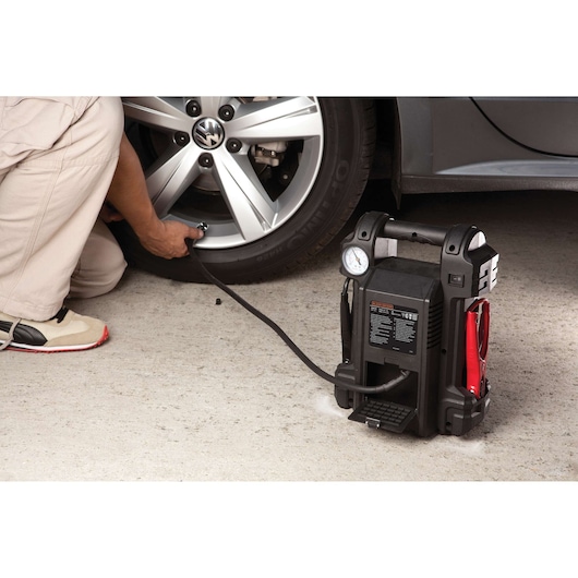 BLACKDECKER JS350CC portable jump starter inflating a car tire, pressure gauge and cables visible.