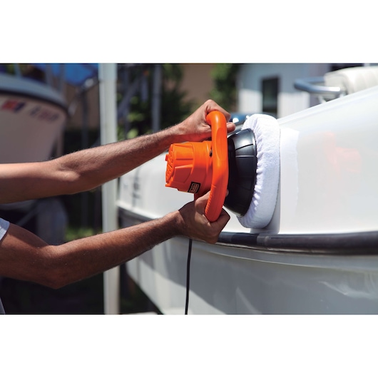 BLACKDECKER KP12K orange polisher being used on a white boat hull outdoors.