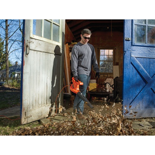 BLACKDECKER LB700 leaf blower used outdoors to clear leaves, shown in action by open shed door.