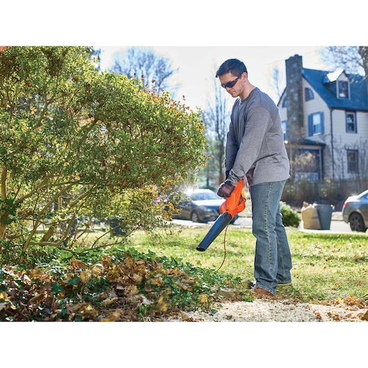 BLACKDECKER LB700 leaf blower held by person removing leaves in a yard, garden setting, outdoor use.