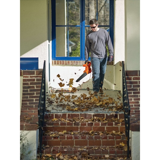 BLACKDECKER LB700 leaf blower photographed clearing leaves from brick steps in outdoor setting.