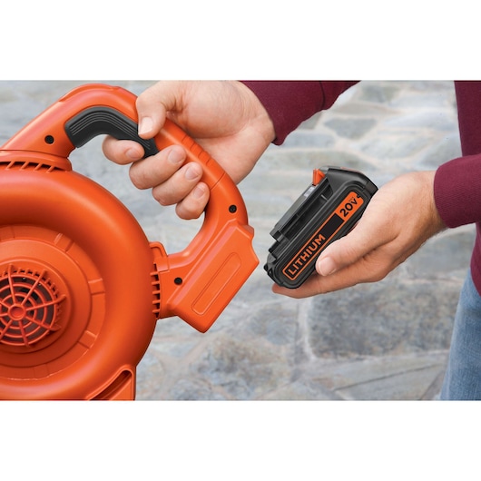 Photo of BLACKDECKER LBXR20 20V lithium battery being inserted into an orange power tool, close-up view.