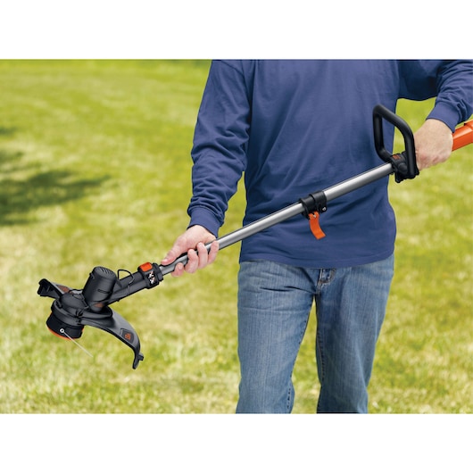Photo of BLACKDECKER LST136 string trimmer held by a person outdoors on grass.