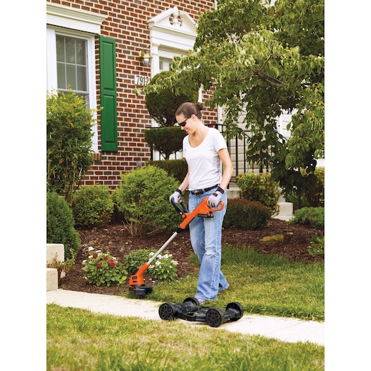 Photo of BLACKDECKER MTC220 string trimmer and mower in use on lawn near flower beds.