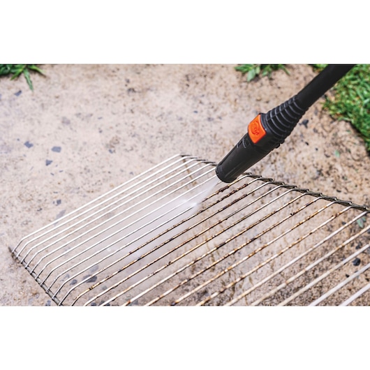 BLACKDECKER PW1450TD pressure washer cleaning metal grill rack outdoors.