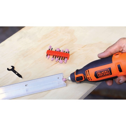 BLACKDECKER RT18KA rotary tool kit grinding metal edge on wood table, orange and black handle visible.