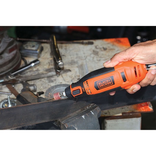 BLACKDECKER RT18KA rotary tool sanding metal on workbench, orange and black handheld power tool.