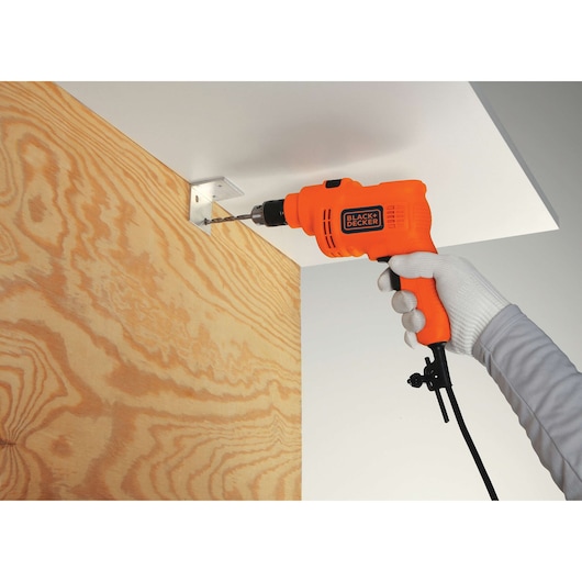 Photo of BLACK+DECKER TP550 corded drill being used to drill into metal bracket on wood panel.