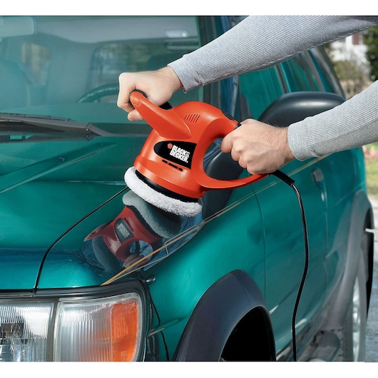 BLACK+DECKER WP900 orange handheld polisher in use on car hood.